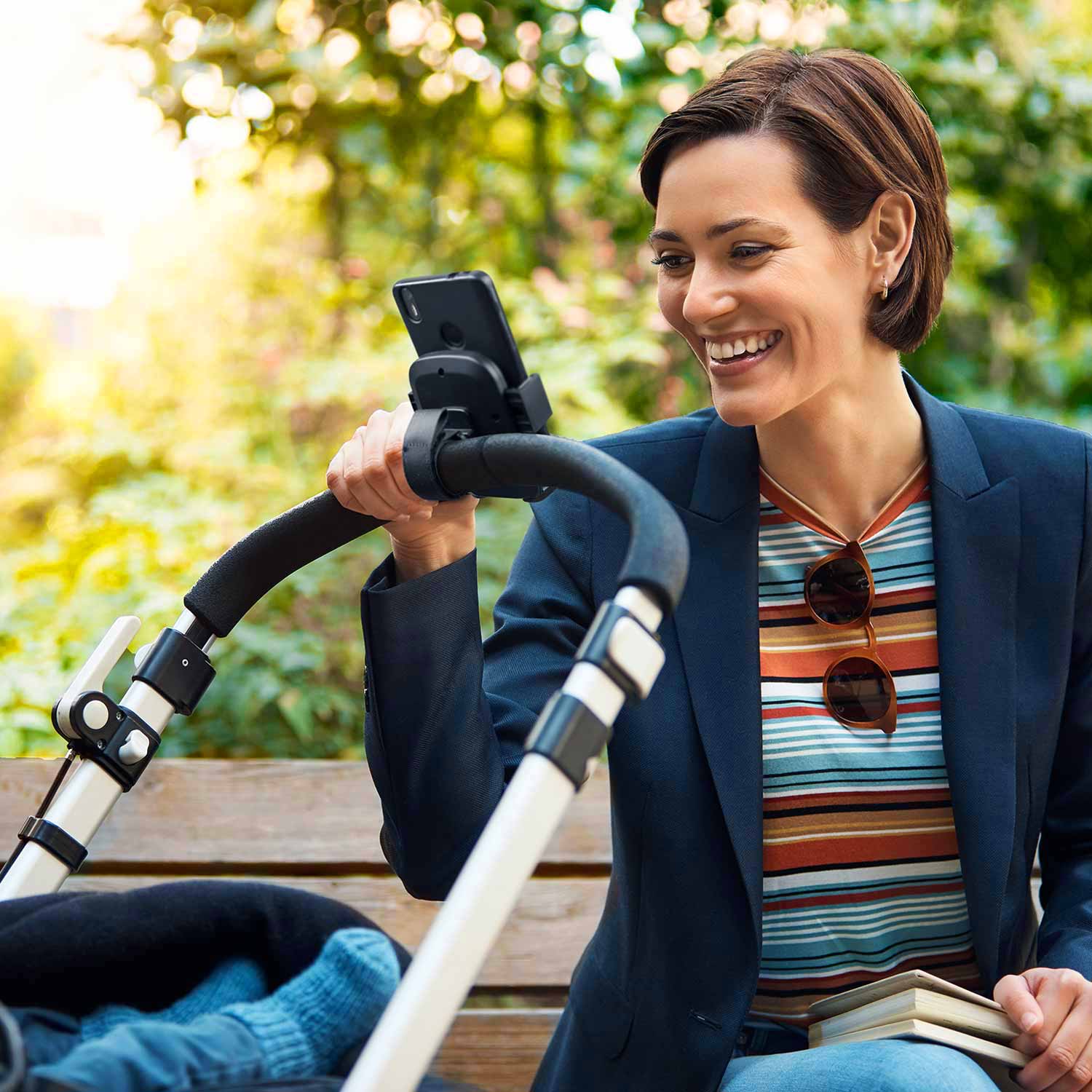 Mujer consultando el teléfono móvil mientras pasea con la silla del bebé